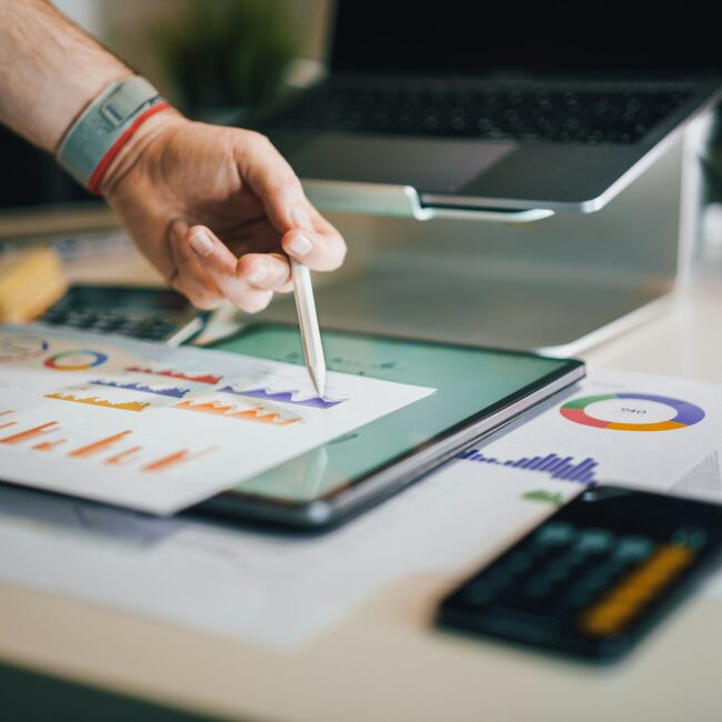 Hand, die mit weißem Stift auf ein Blatt mit einer Statistik zeigt