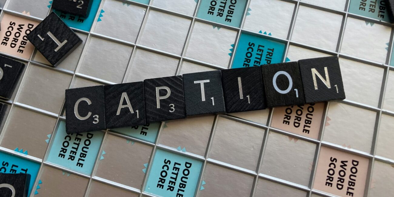 Wort "Caption", das aus Scrabble-Steinen gebaut ist und auf dem Spielbrett liegt