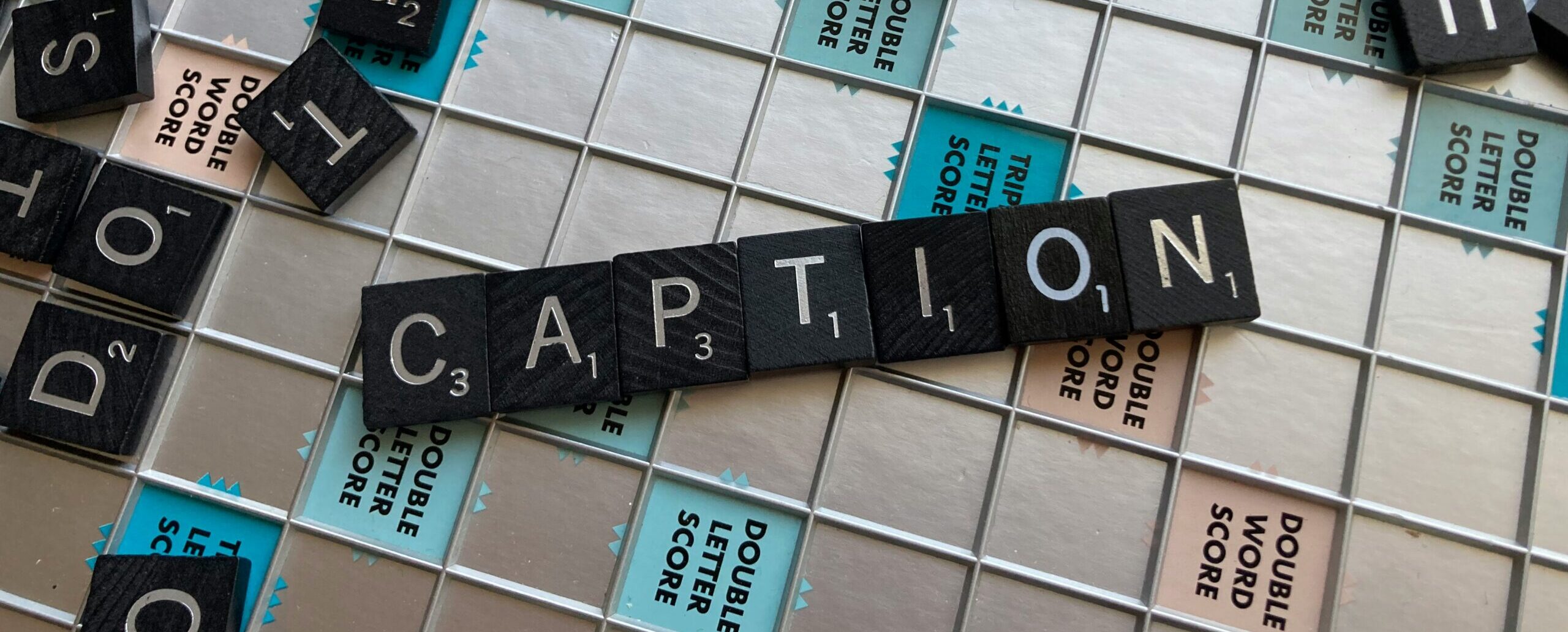 Wort "Caption", das aus Scrabble-Steinen gebaut ist und auf dem Spielbrett liegt